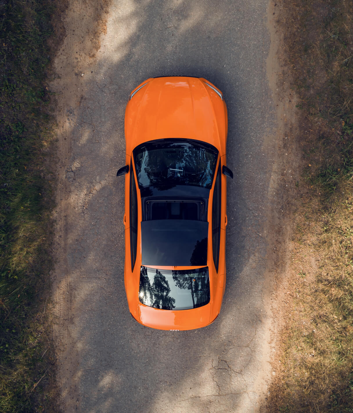 Birds eye view of an orange convertible on a road.